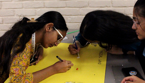 Students designing an app interface on a laptop